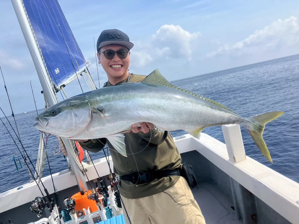 愁輝丸で釣り上げた青物を掲げる大橋正義氏