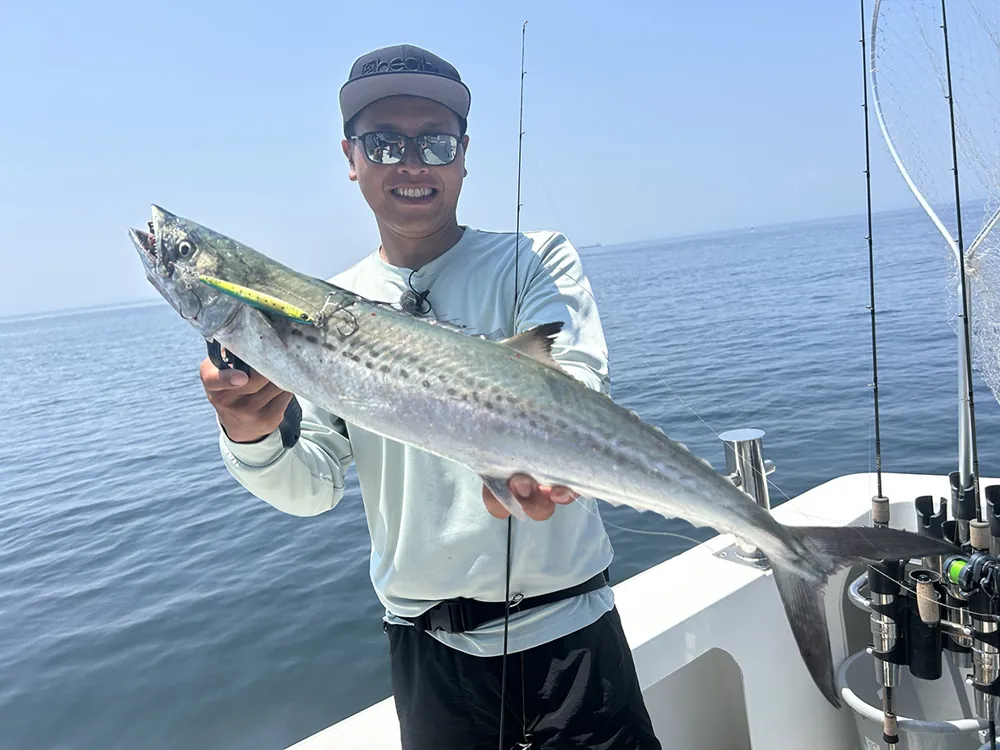 ジグで釣り上げたサワラを掲げる大橋正義氏